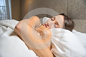 Young pretty caucasian woman hugging pillow while sleeping on bed in hotel room