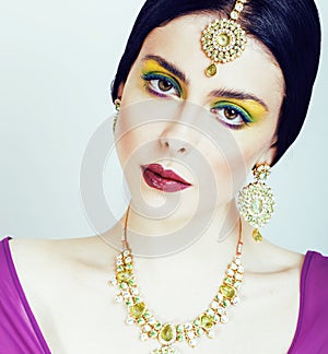 Young pretty caucasian woman like indian in ethnic jewelry close up on white, bridal bright makeup fashion