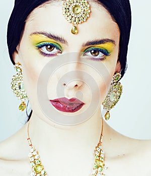 Young pretty caucasian woman like indian in ethnic jewelry close up on white, bridal makeup