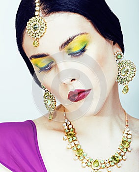 Young pretty caucasian woman like indian in ethnic jewelry close up on white, bridal makeup