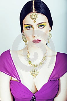 Young pretty caucasian woman like indian in ethnic jewelry close up on white, bridal makeup