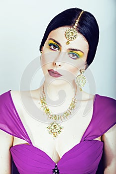 Young pretty caucasian woman like indian in ethnic jewelry close up on white, bridal makeup