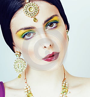 Young pretty caucasian woman like indian in ethnic jewelry close up on white, bridal makeup