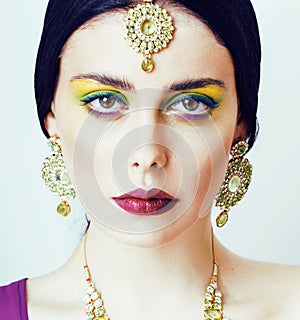 Young pretty caucasian woman like indian in ethnic jewelry close up on white, bridal makeup