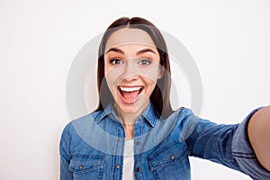 Young pretty cheerful girl in jeans shirt taking self-portrait