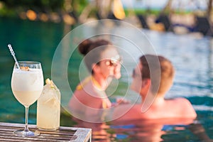 young pretty couple enjoing summer evening with cocktails in luxury pool