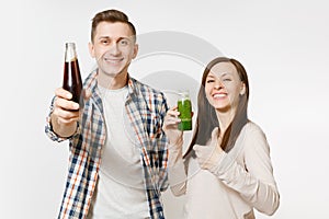 Young pretty couple man and woman holding green detox smoothies, cola in glass bottle isolated on white background photo
