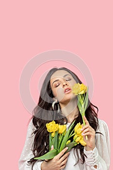 Young pretty dark-haired woman holding yellow flowers and looking relaxed