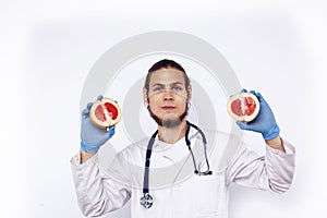 Young pretty doctor with stethoscope holding fruits, healthy food care concept