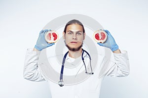 Young pretty doctor with stethoscope holding fruits, vegetables and pills, healthy food care concept