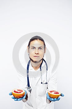 Young pretty doctor with stethoscope holding fruits, vegetables and pills, syringe, healthy food care concept