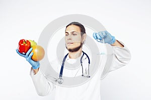 Young pretty doctor with stethoscope holding fruits, vegetables and pills, syringe, healthy food care concept