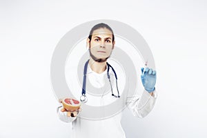 Young pretty doctor with stethoscope holding fruits, vegetables and pills, syringe, healthy food care concept