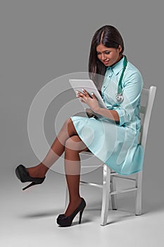 Young pretty doctor with stethoscope sitting on a chair