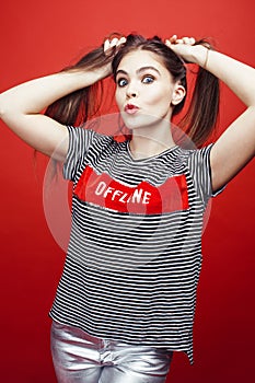 Young pretty emitonal posing teenage girl on bright red background, happy smiling lifestyle people concept