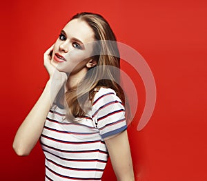 young pretty emitonal posing teenage girl on bright red background, happy smiling lifestyle people concept