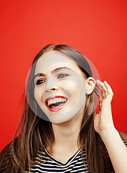 Young pretty emitonal posing teenage girl on bright red background, happy smiling lifestyle people concept