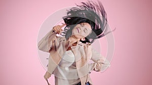 Young pretty expressive girl in pink jacket dancing. Fashion model with brunette hairs move the body at studio on