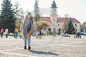 young pretty fashionable woman walking in brown coat by street