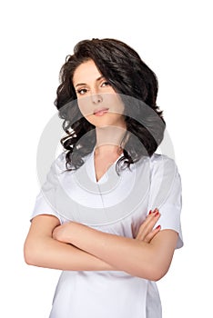 Young pretty female doctor in uniform keeping arms crossed and looking at camera isolated on white background.