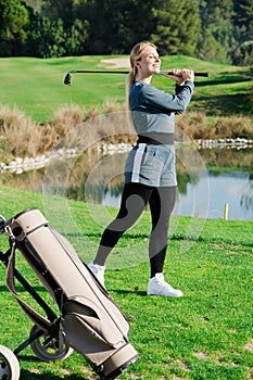 Young pretty female golf player is succeeded in ball hitting