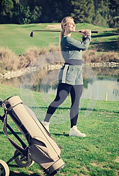 Young pretty female golf player is succeeded in ball hitting