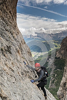 Young pretty female mountain climber on a Via Ferrata in the Dolomites in Alta Badia