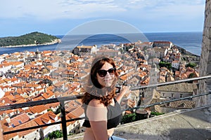 A young pretty female tourist posing on top of the Walls of Dubrovnik overlooking the old town of Dubrovnik, Croatia