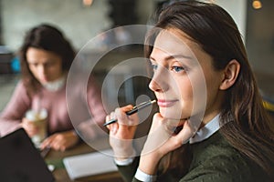 Young pretty females working with notes and laptop in cafe