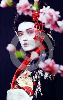 young pretty geisha in kimono with sakura and decoration on blac