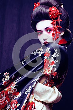 young pretty geisha in kimono with sakura and decoration on blac