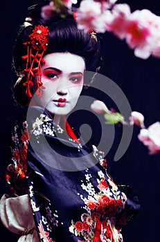 young pretty geisha in kimono with sakura and decoration on blac