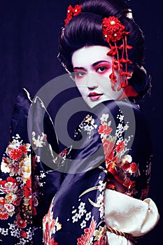 young pretty geisha in kimono with sakura and decoration on blac