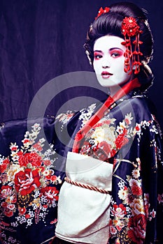 Young pretty geisha in kimono with sakura and decoration on blac