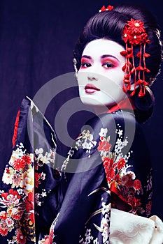 young pretty geisha in kimono with sakura and decoration on blac