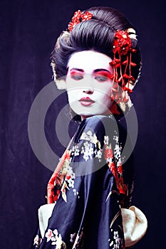 young pretty geisha in kimono with sakura and decoration on blac