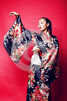 Young pretty geisha on red background posing in kimono, oriental people concept