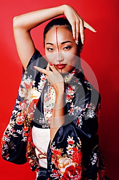 Young pretty geisha on red background posing in kimono, oriental people concept close up