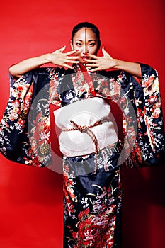 Young pretty geisha on red background posing in kimono, oriental people concept close up