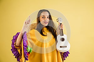 Young pretty girl in bright garment and sombrero isolated over yellow background