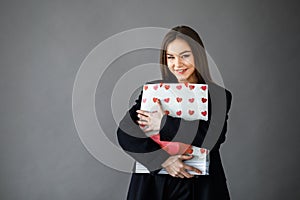 Young pretty girl in business style clothes stands on gray background with paper bags in hands. Business style