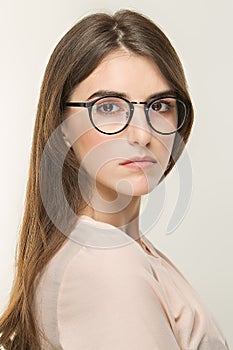 Young pretty girl, classic portrait on the white background. Nude style, office look in glass. Optica photo