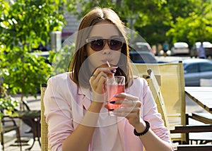Young pretty girl drinks a cold beverage, outdoor