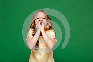 Young pretty girl eating raspberry over green background.