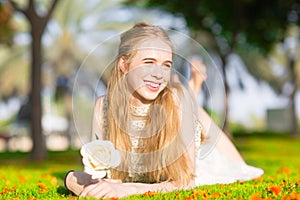A young pretty girl holding a white rose in a sunny park.