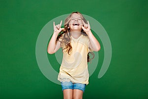 Young pretty girl laughing over green background.