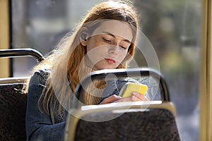 Young pretty girl passenger using mobile phone  in modern tram