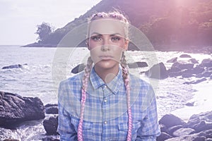 Young pretty girl with pink plaits between rocks