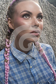 Young pretty girl with pink plaits between rocks