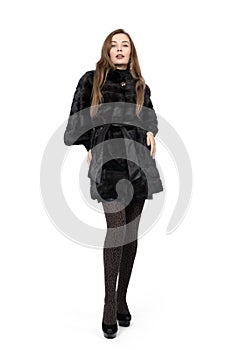 Young pretty girl posing in dark short mink fur coat, full height isolated on white background